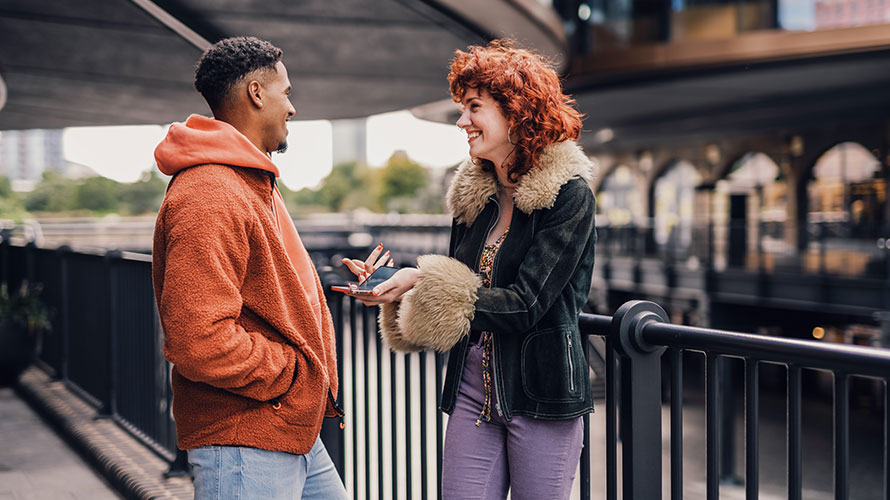 A Man And A Woman Talking By A Railing Image